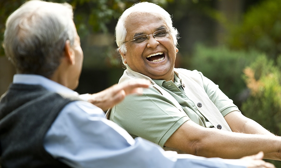 A pair of senior men laughing together in the sunshine