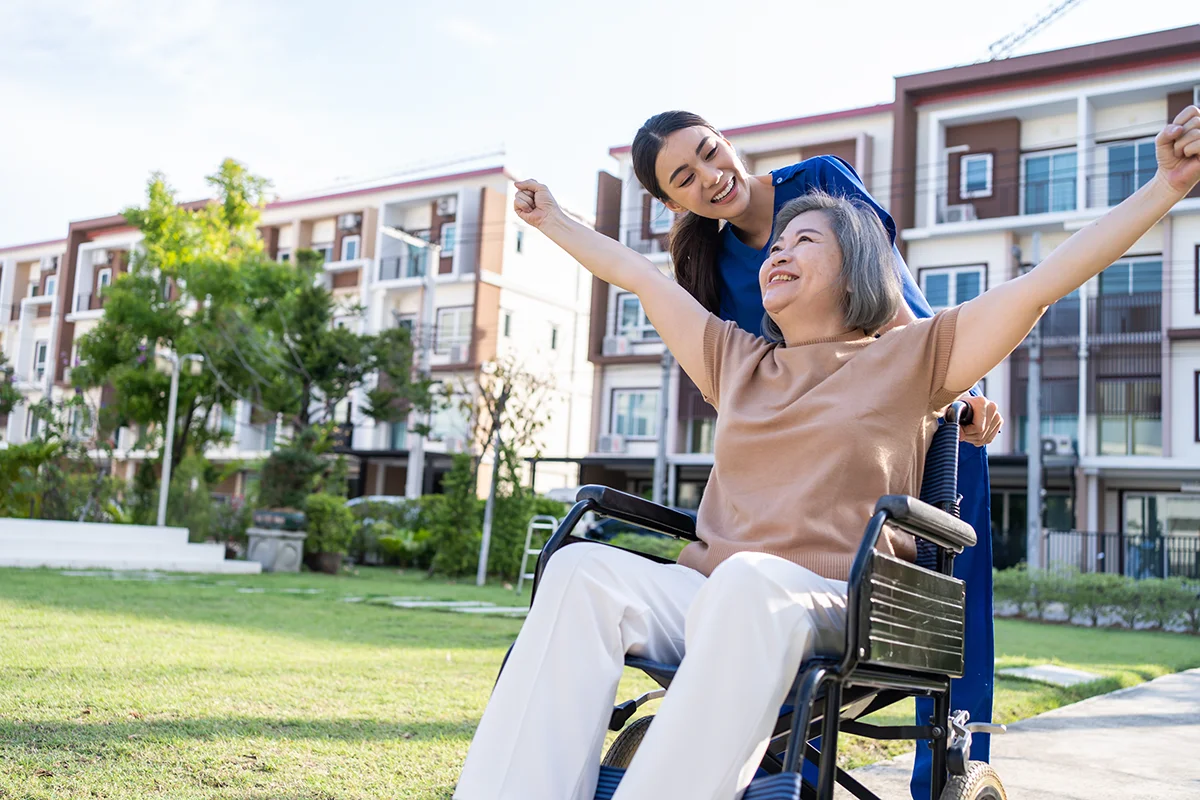 Nurse pushing a joyful elderly woman in a wheelchair
