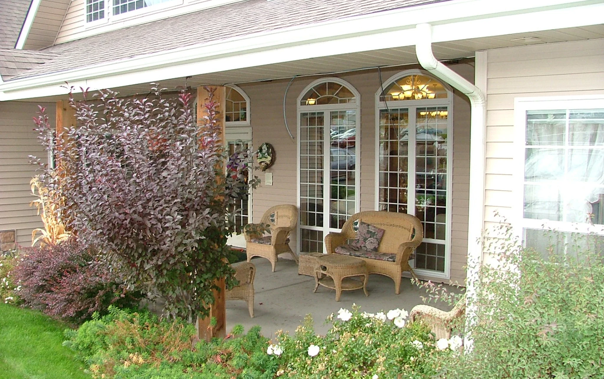 Well-furnished porch facing a yard full of varied shrubbery