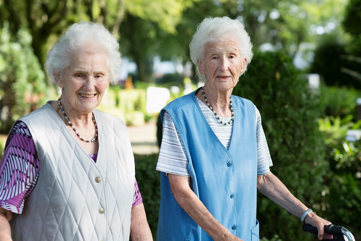 Happy pair of senior women out for a stroll through the park together