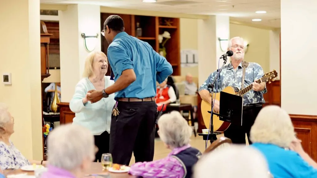 Senior resident and caregiver dancing and playing music