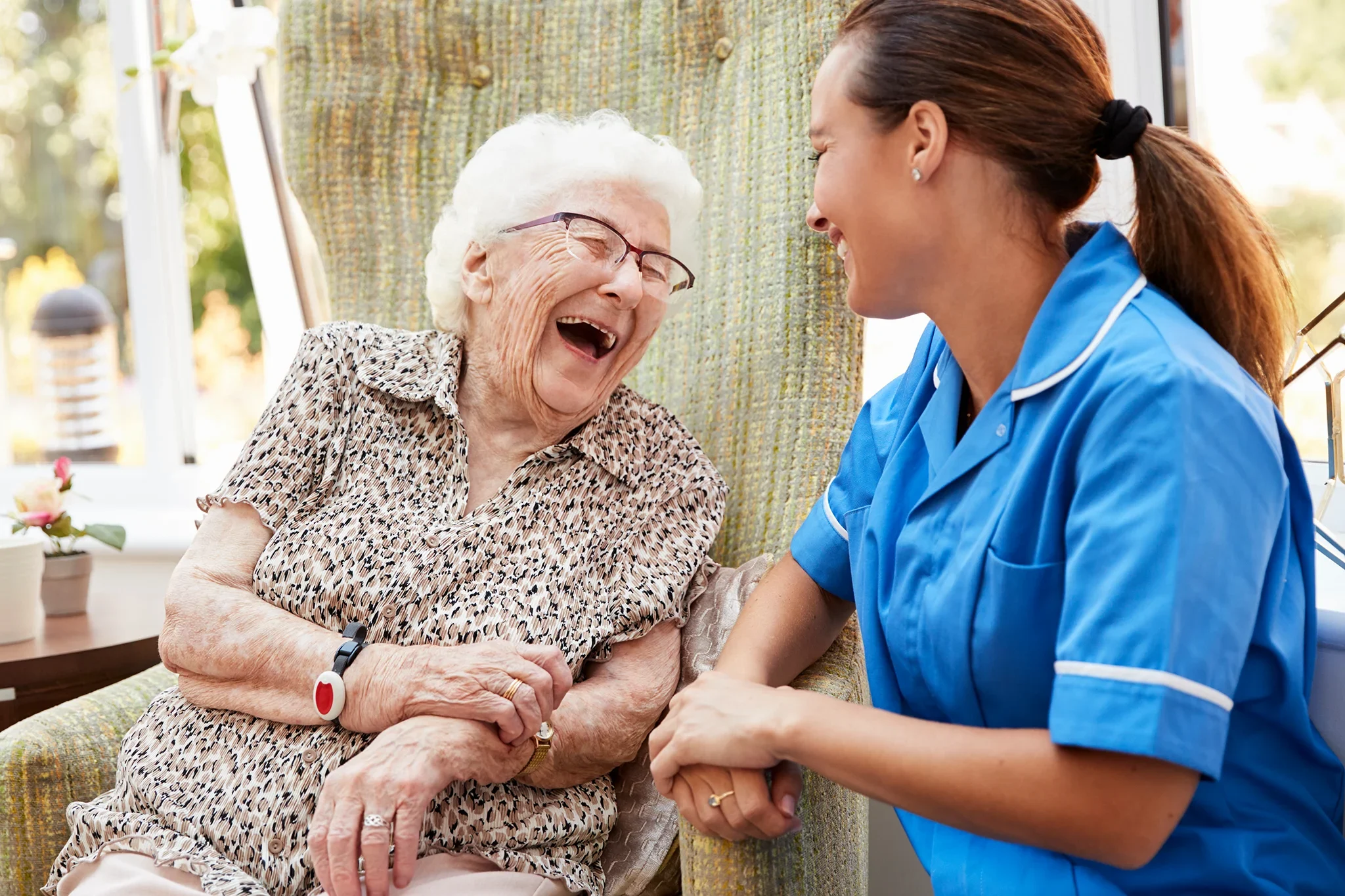 Senior woman and female caretaker laughing together