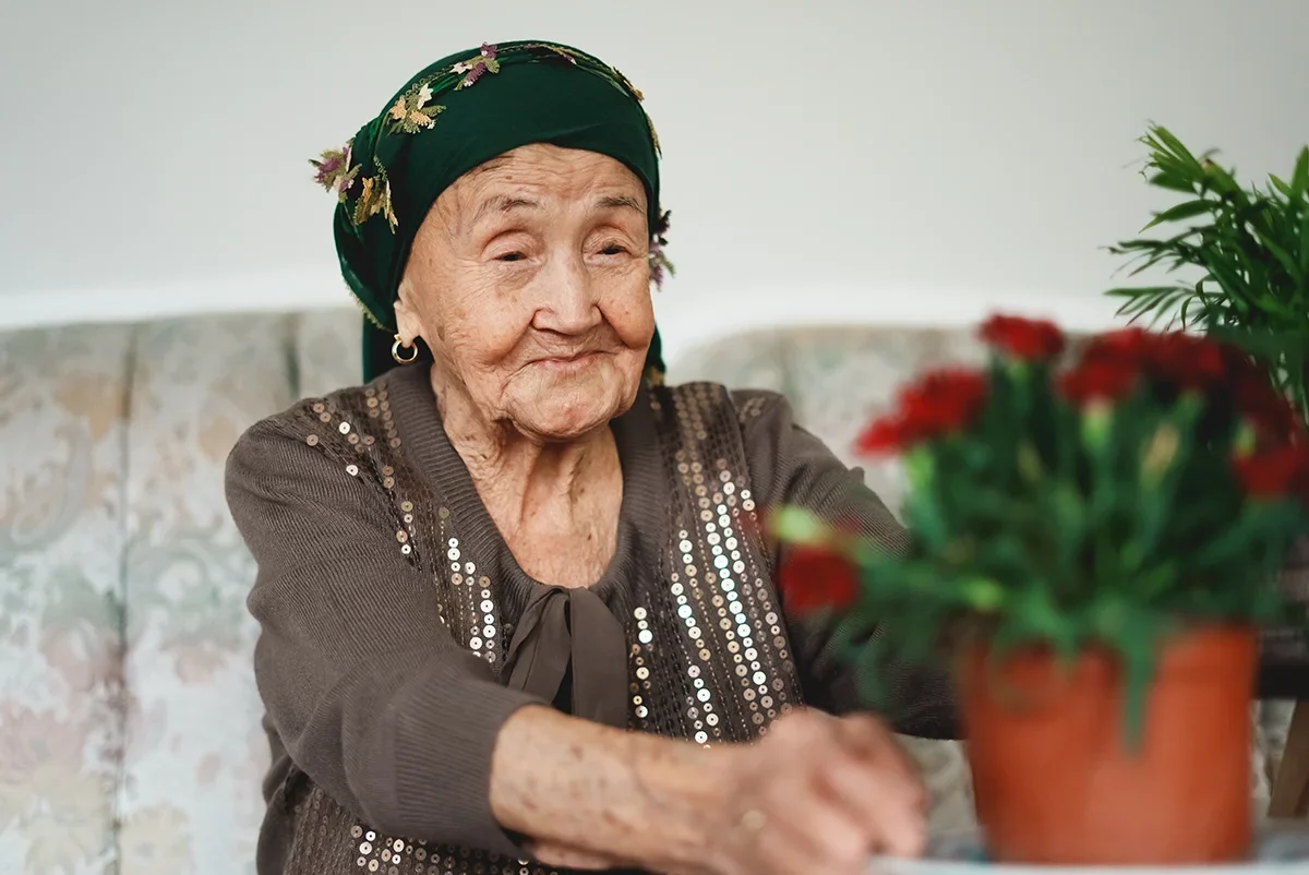 Elderly Asian woman enjoying some flowers