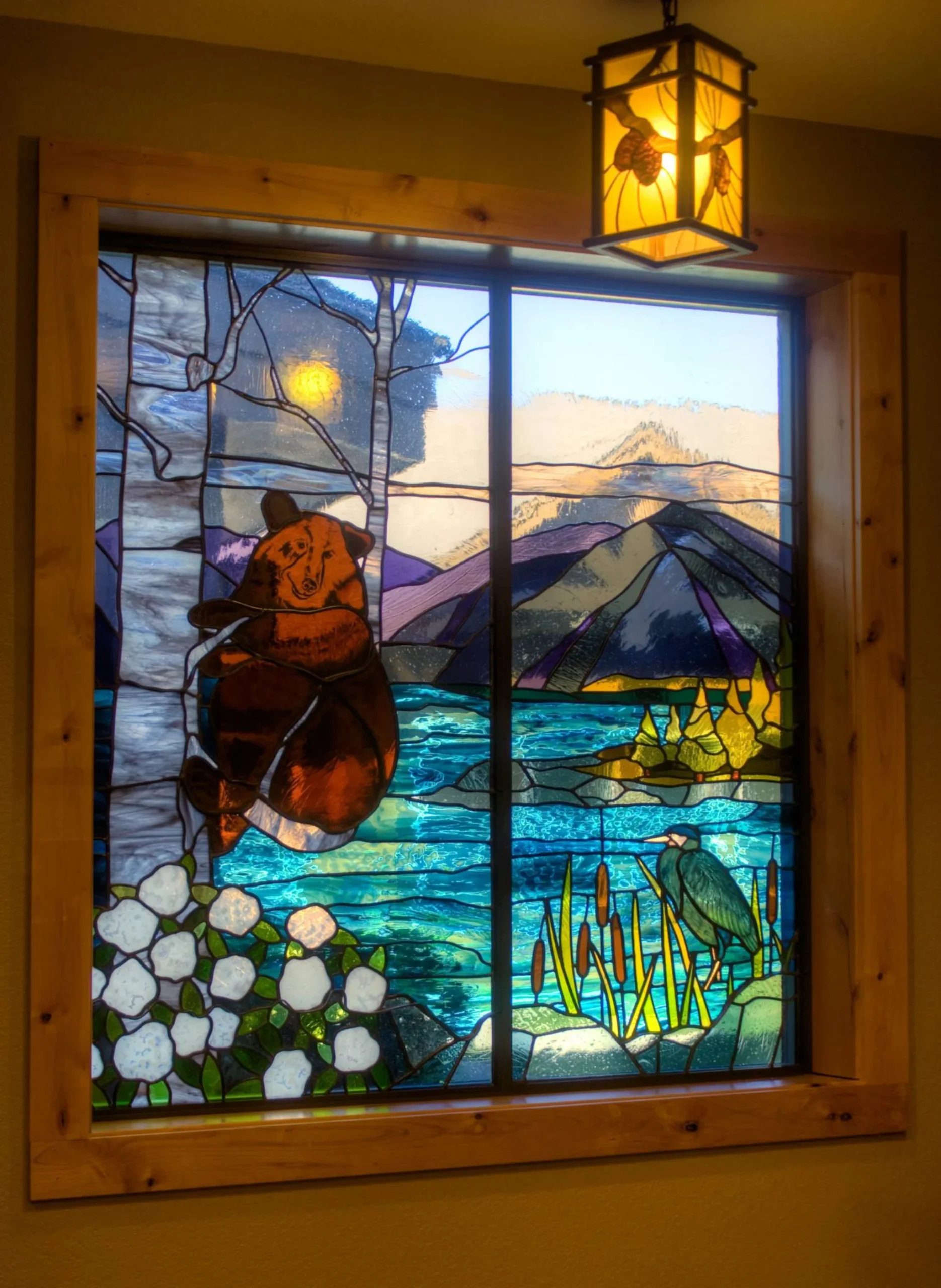 A stained glass window depicting a bear climbing a tree with a mountain lake in the background