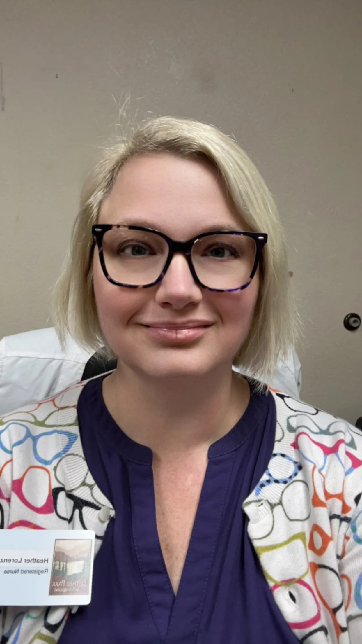 A smiling middle aged woman with cat-eye glasses and platinum blond hair