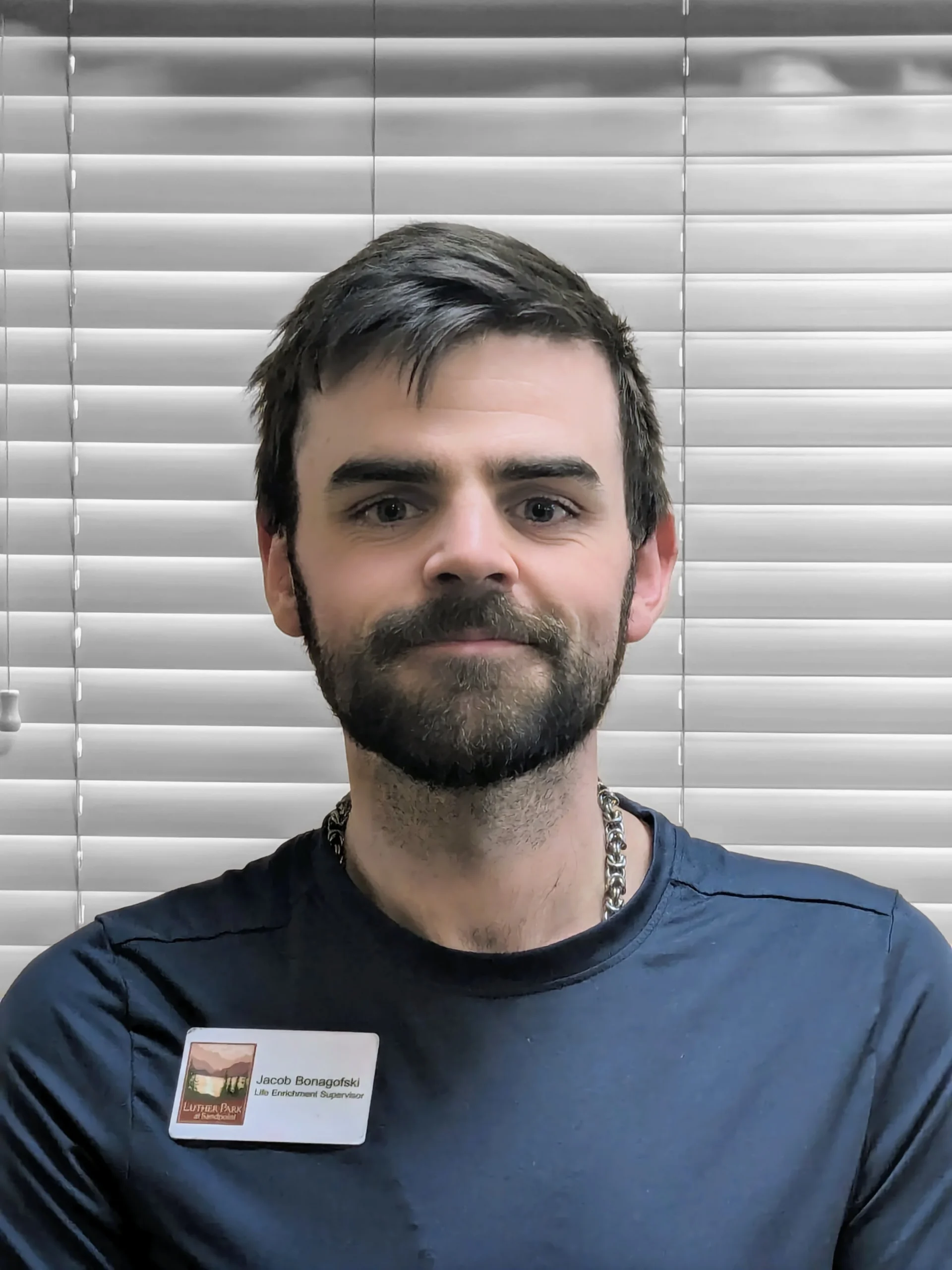 A smiling middle aged man with dark hair and a beard