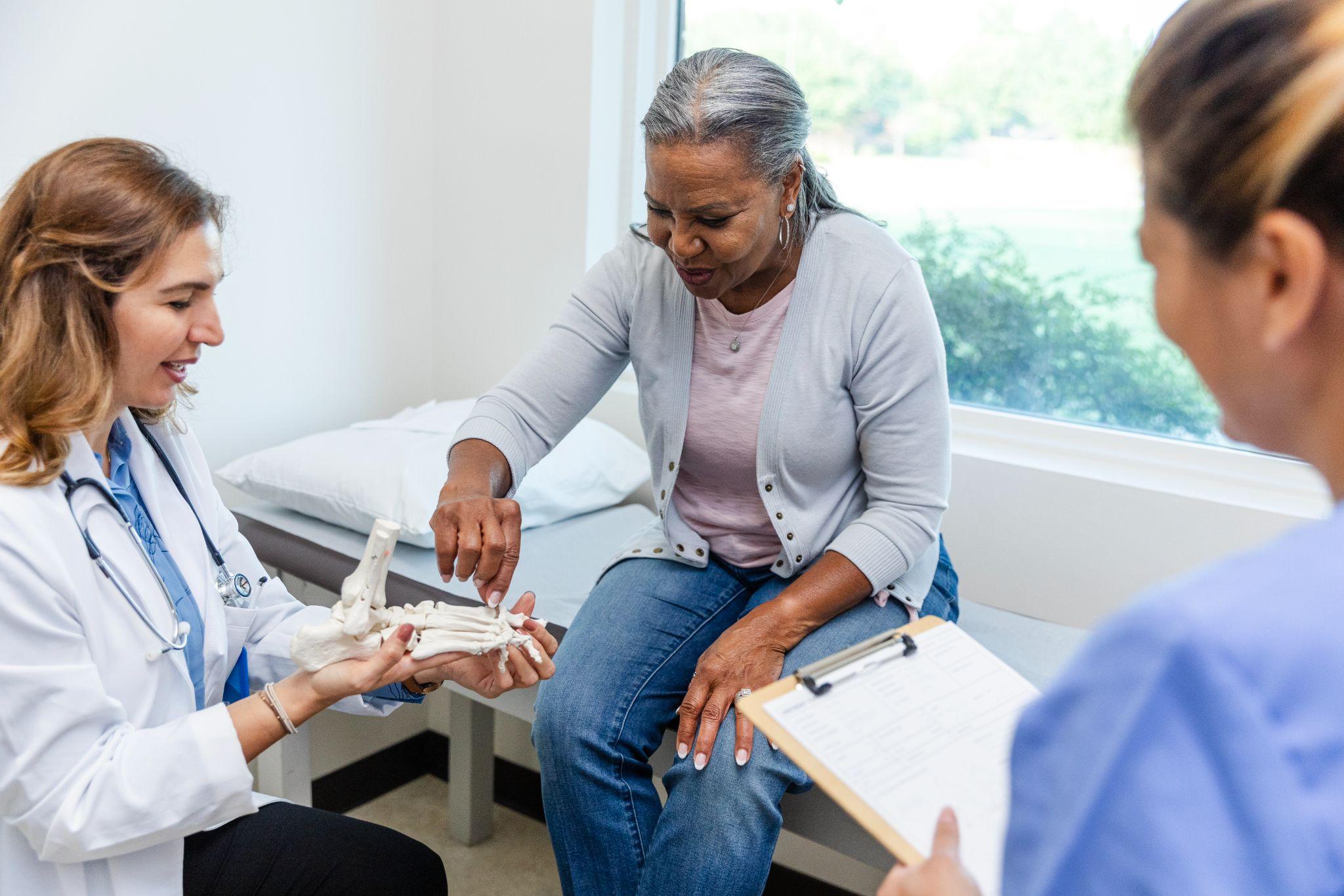 An older woman at the doctor with a nurse, talking about bone health